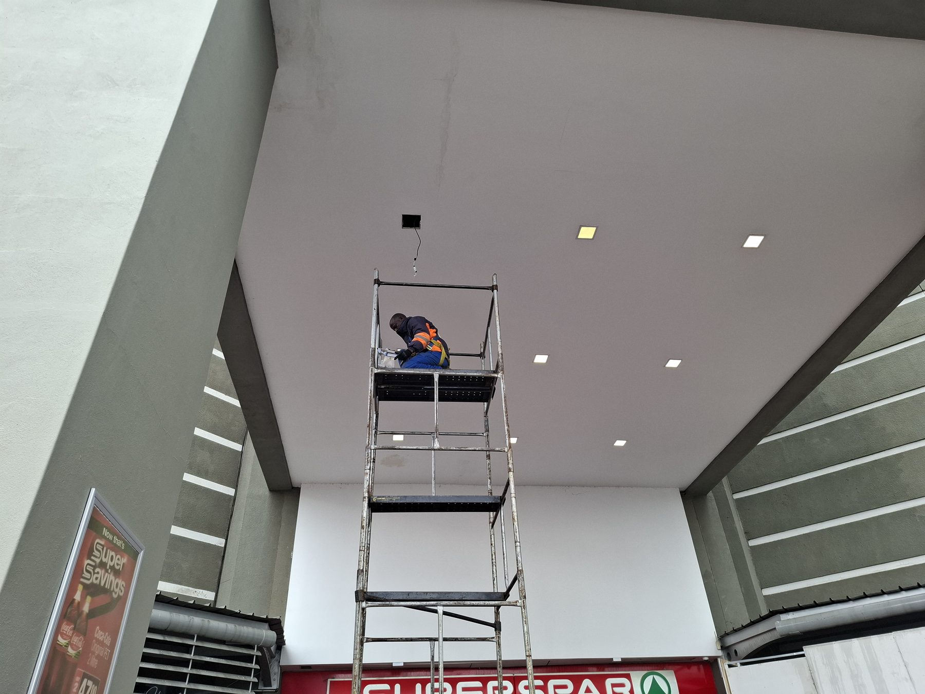 Technician on scaffolding with open ceiling aperture visible