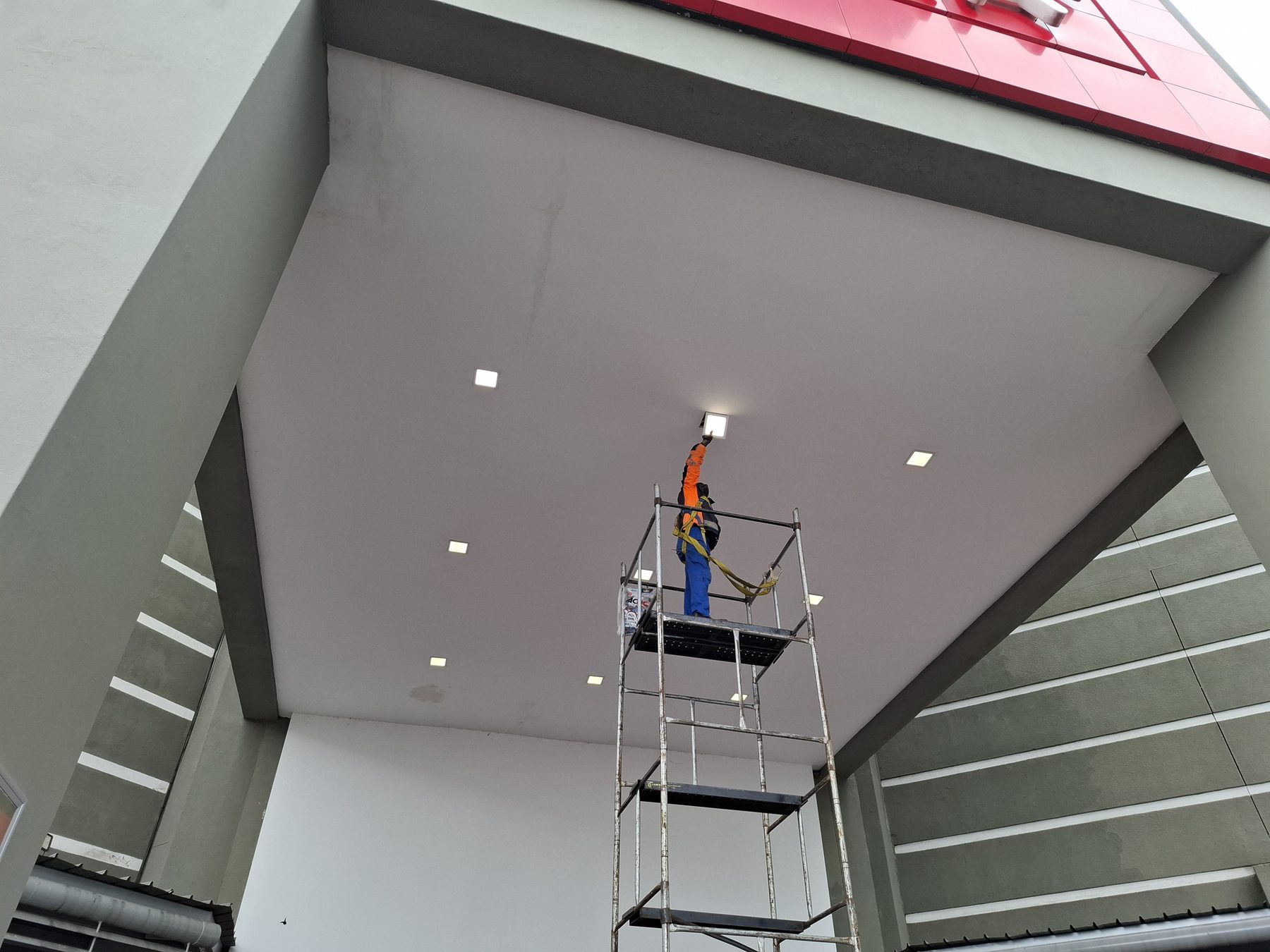 Technician installing the new LED downlight fitting at height