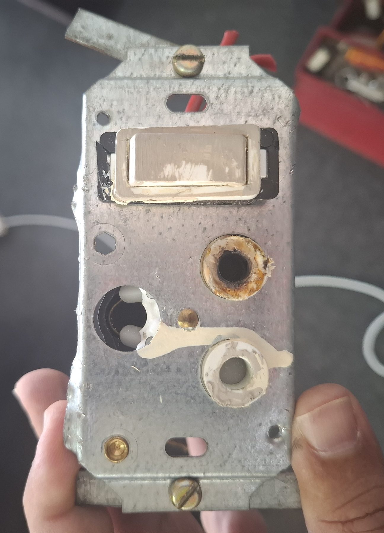 Switch and socket mounting box removed from the wall, showing heat damage and corrosion